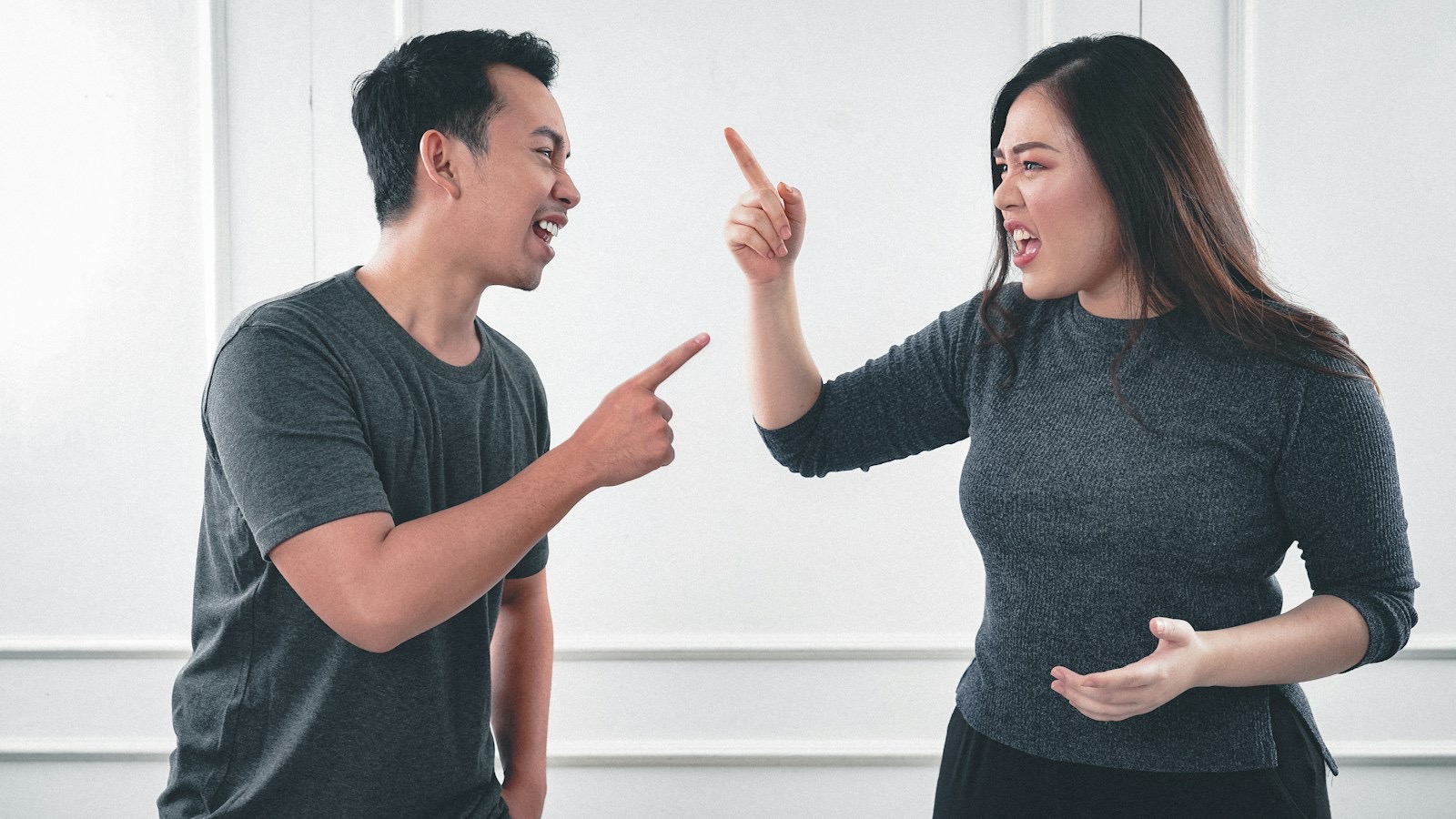 A man and a woman pointing at each other mid-argument